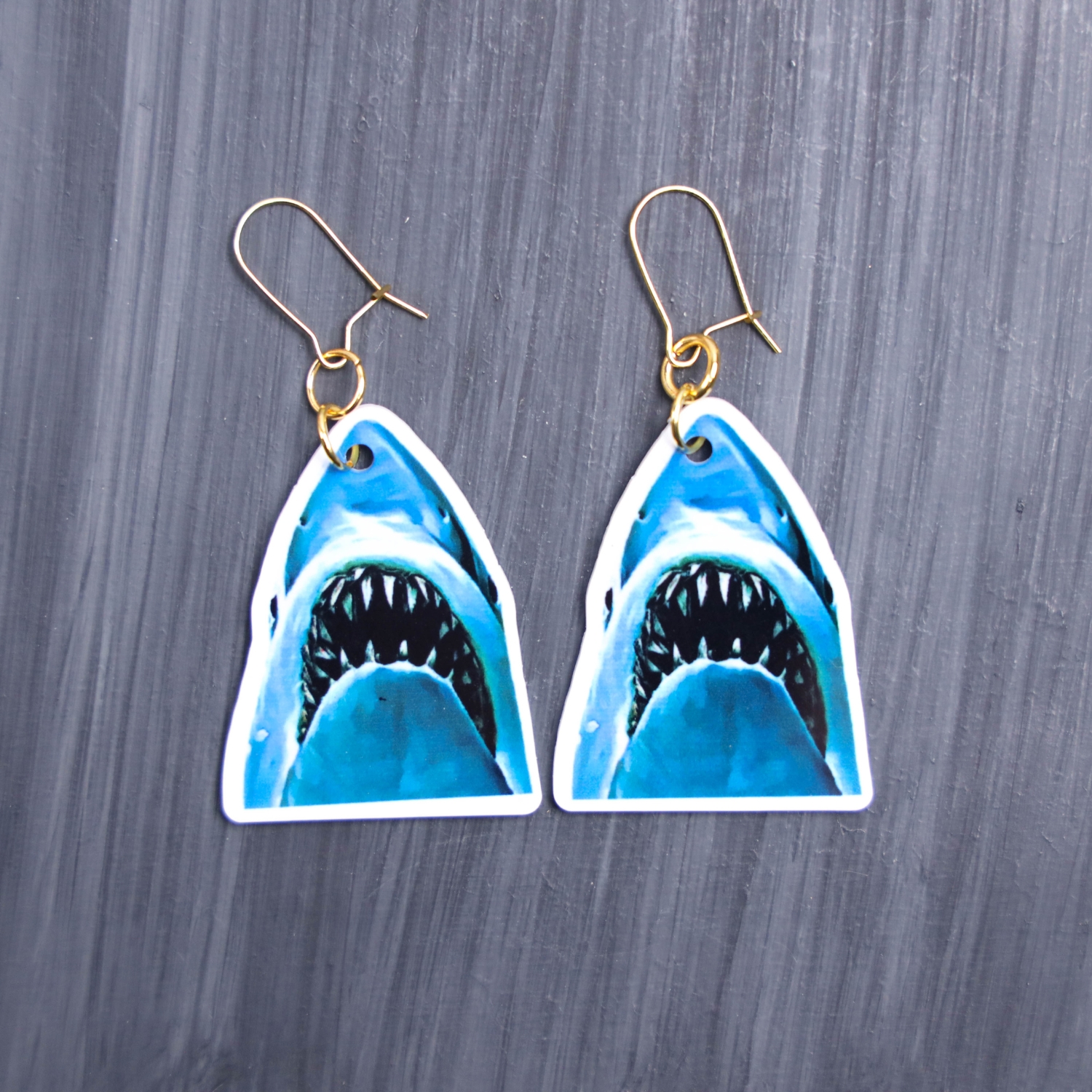Jaws Earrings. These earrings are made with acrylic and hand heat pressed. Comes with 18k plated gold hooks that is nickel free. Easily put loop through ear and hook back so the earring doesn’t fall out.