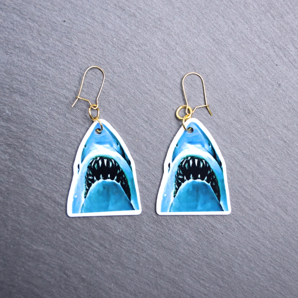 Jaws Earrings. These earrings are made with acrylic and hand heat pressed. Comes with 18k plated gold hooks that is nickel free. Easily put loop through ear and hook back so the earring doesn’t fall out.