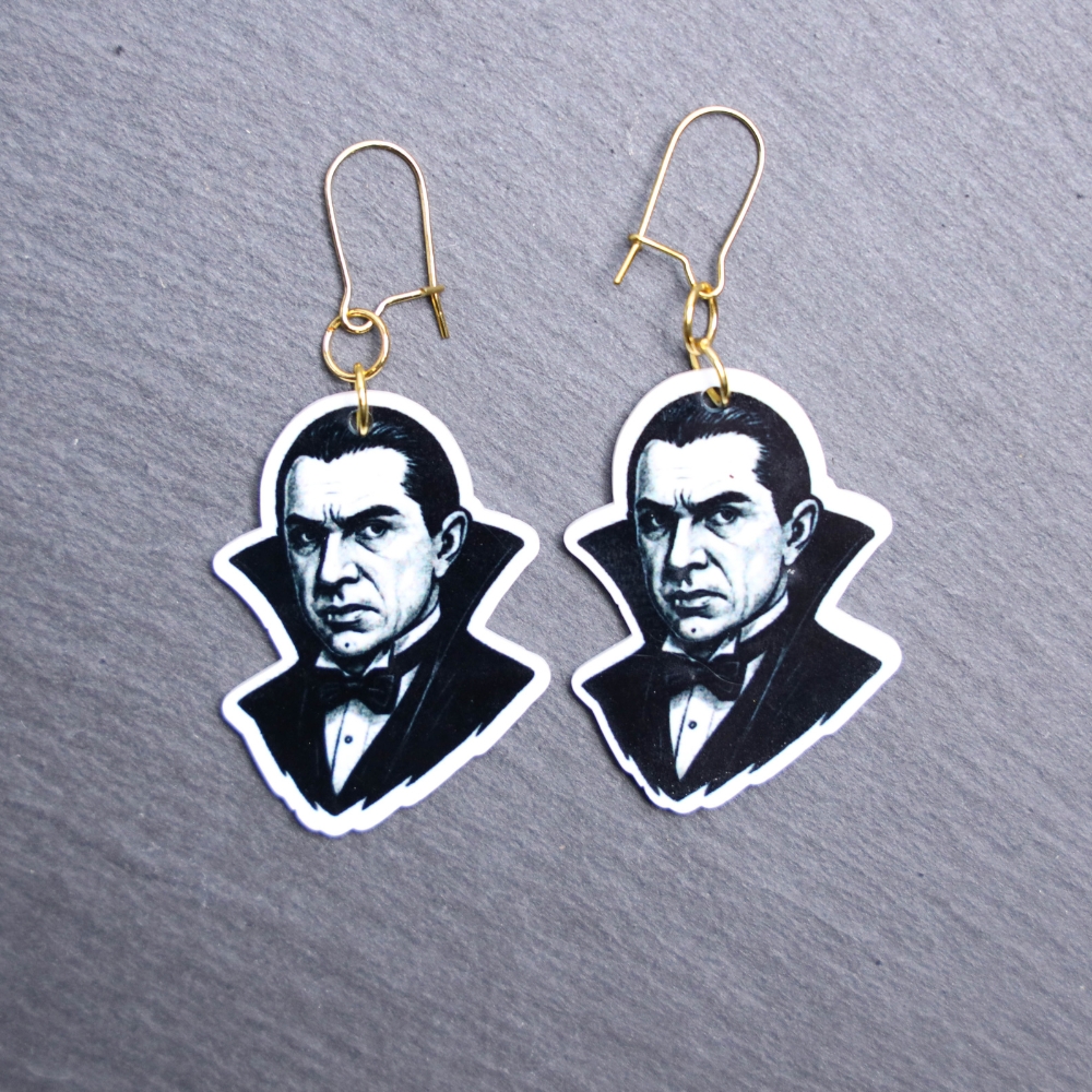 Dracula Earrings. These earrings are made with acrylic and hand heat pressed. Comes with 18k plated gold hooks that is nickel free. Easily put loop through ear and hook back so the earring doesn’t fall out.