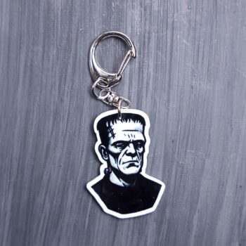 Frank Bag Tag. This bag tag is made with acrylic and heat pressed. Comes with lobster clasp topper that easily hooks to a bag, zippers, and lanyards for fun display and swivels. White backside.