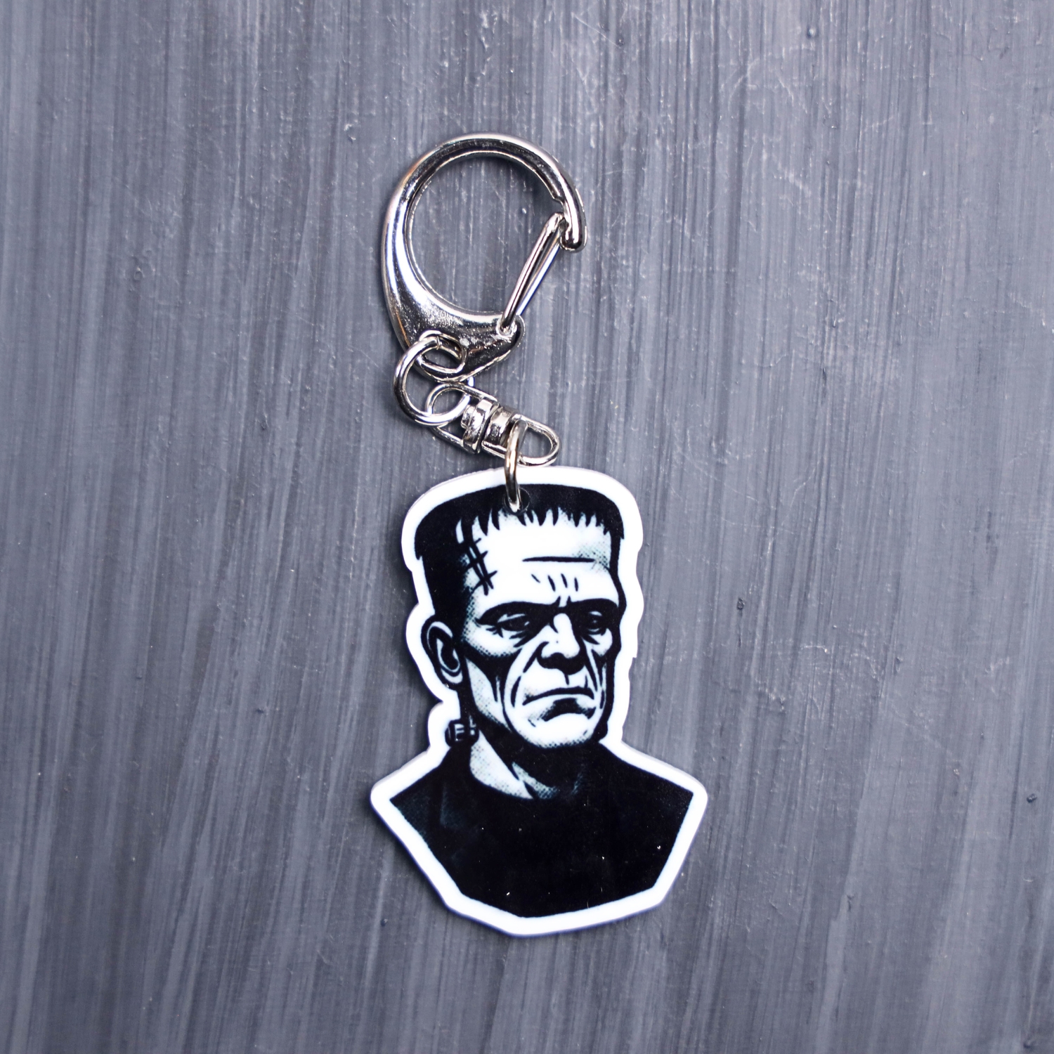 Frank Bag Tag. This bag tag is made with acrylic and heat pressed. Comes with lobster clasp topper that easily hooks to a bag, zippers, and lanyards for fun display and swivels. White backside.