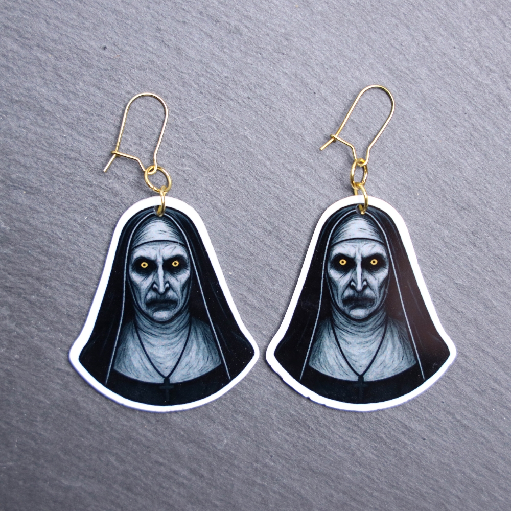 Nun Earrings. These earrings are made with acrylic and hand heat pressed. Comes with 18k plated gold hooks that is nickel free. Easily put loop through ear and hook back so the earring doesn’t fall out.