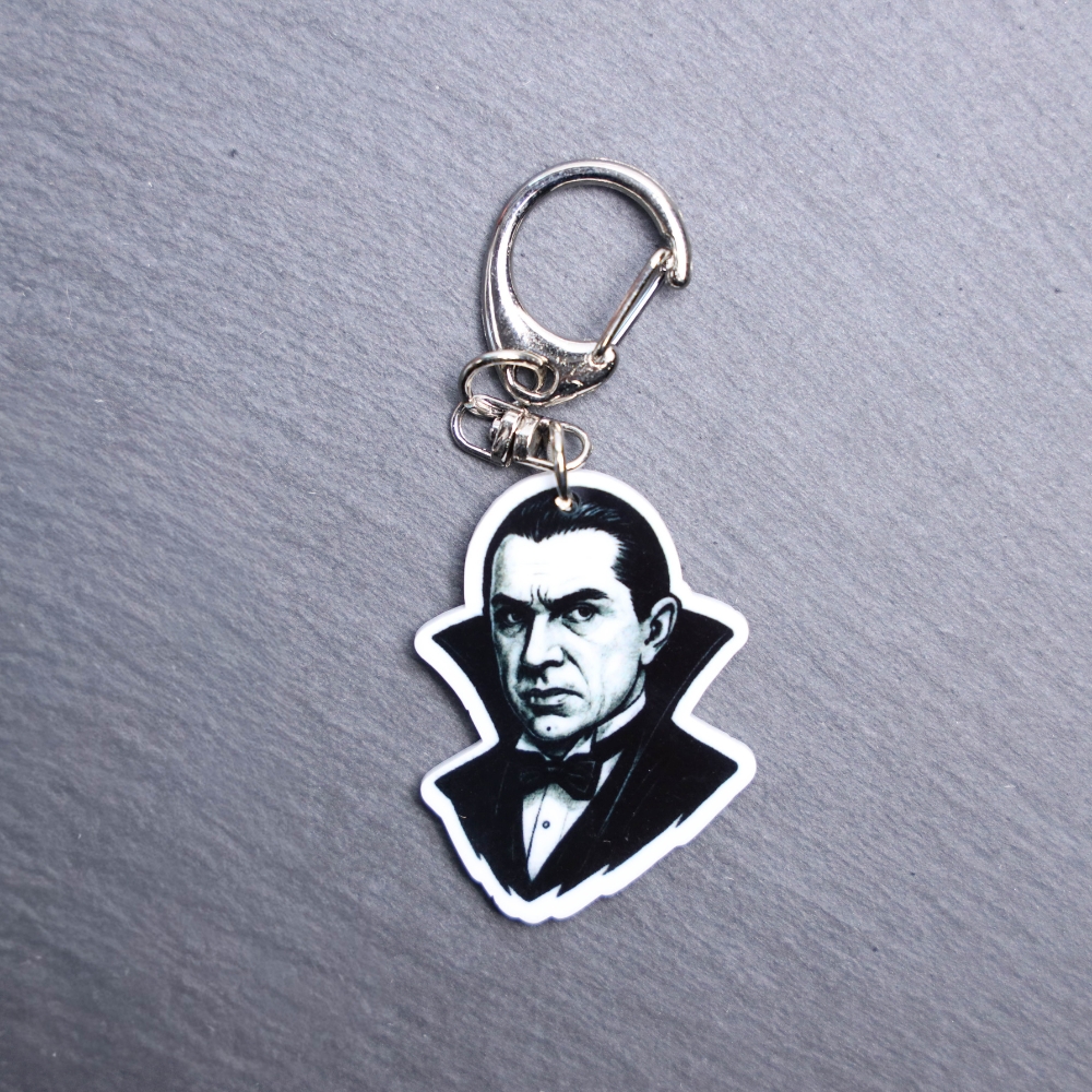 Dracula Bag Tag. This bag tag is made with acrylic and heat pressed. Comes with lobster clasp topper that easily hooks to a bag, zippers, and lanyards for fun display and swivels. White backside.