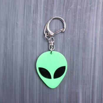 Alien Head Neon Green Bag Tag with black eyes and black backing. Acrylic designed charm with a swivel lobster snap hook in high quality metal alloy.