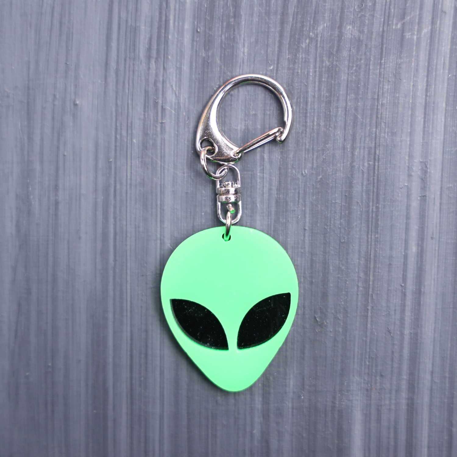 Alien Head Neon Green Bag Tag with black eyes and black backing. Acrylic designed charm with a swivel lobster snap hook in high quality metal alloy.