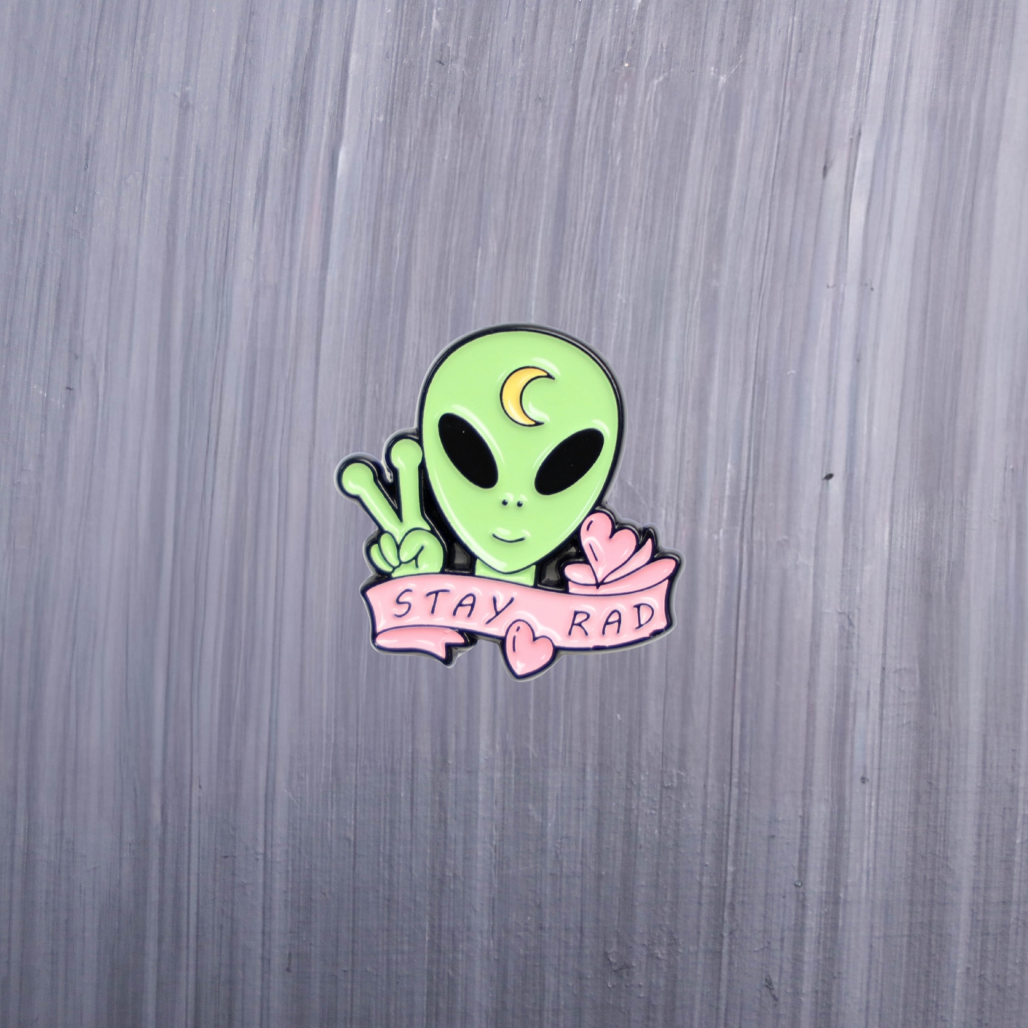 Alien Stay Rad Enamel Pin green alien with pink and moon on his head. These enamel pins are made with metal. These enamel pins are colorful, with a black backing.
