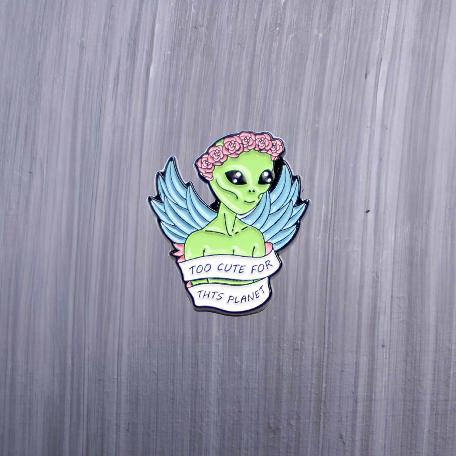 Alien Too Cute For This Planet Enamel Pin with green and pink roses. These enamel pins are made with metal. These enamel pins are colorful, with a black backing.