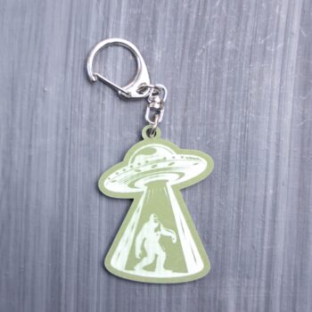 Bigfoot Alien Abduction Green Bag Tag with spaceship. Acrylic designed charm with a swivel lobster snap hook in high quality metal alloy.