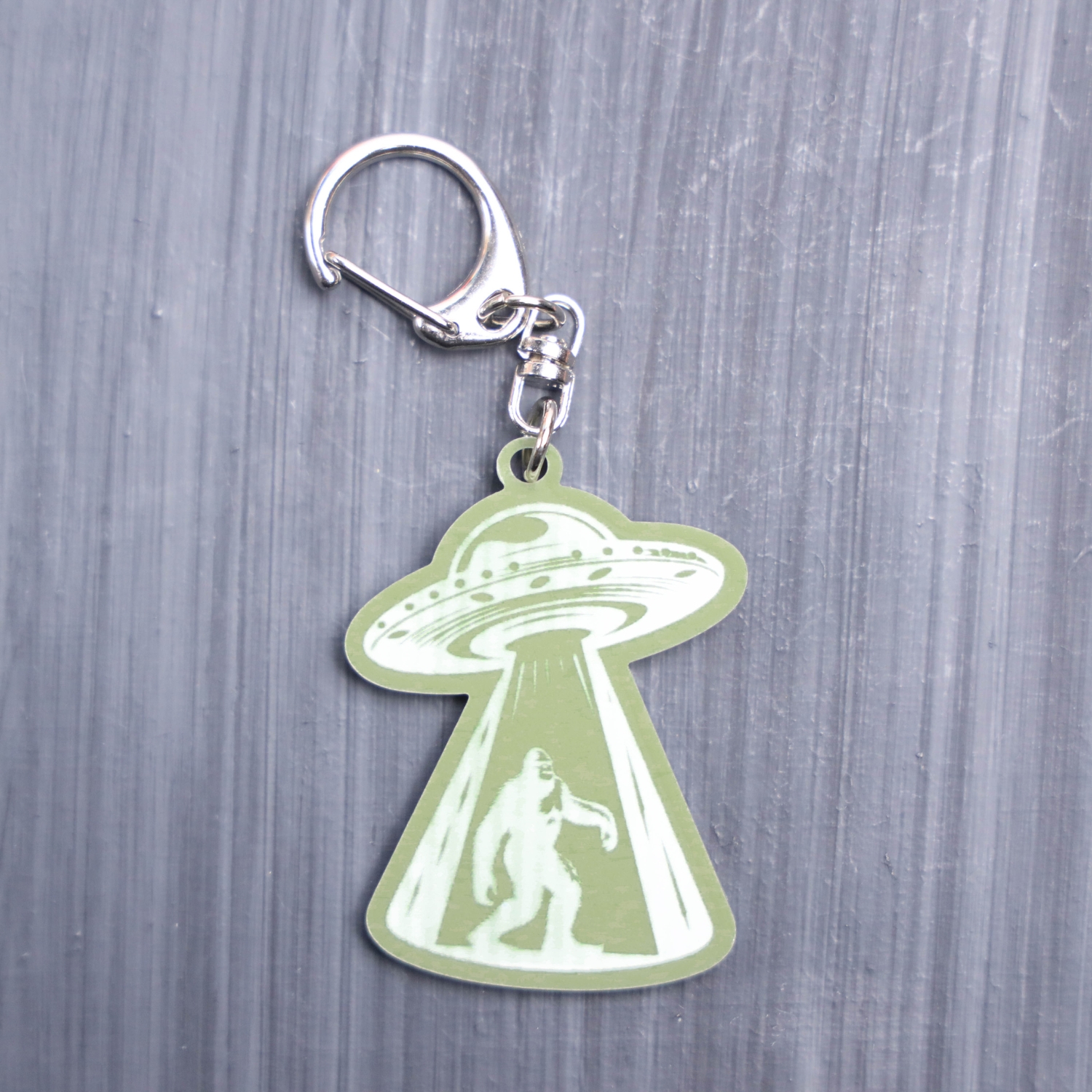Bigfoot Alien Abduction Green Bag Tag with spaceship. Acrylic designed charm with a swivel lobster snap hook in high quality metal alloy.