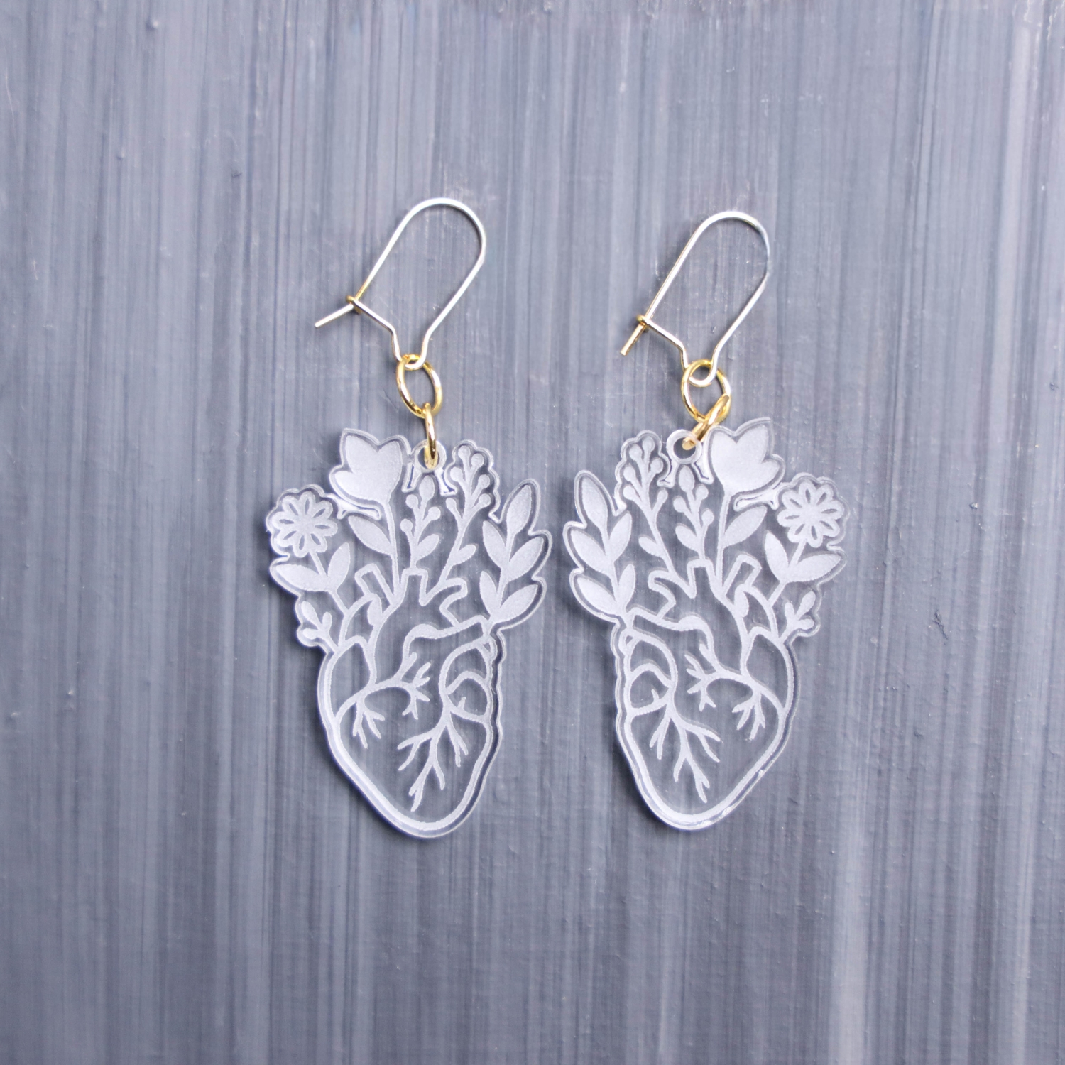 Floral Anatomical Heart Earrings. These earrings are made with clear acrylic. Comes with gold hooks that is nickel free.