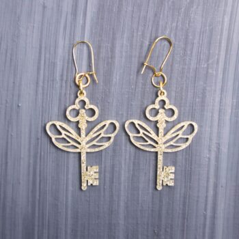Flying Keys Earrings. These earrings are made with gold glitter acrylic. Comes with gold hooks that is nickel free. Features: Approximately 1.5″ In Height Gold Hooks  Nickel Free 1/8″ Thin Acrylic Check out our Instagram for more pictures and videos of this product. Colors may vary due to screen resolution.