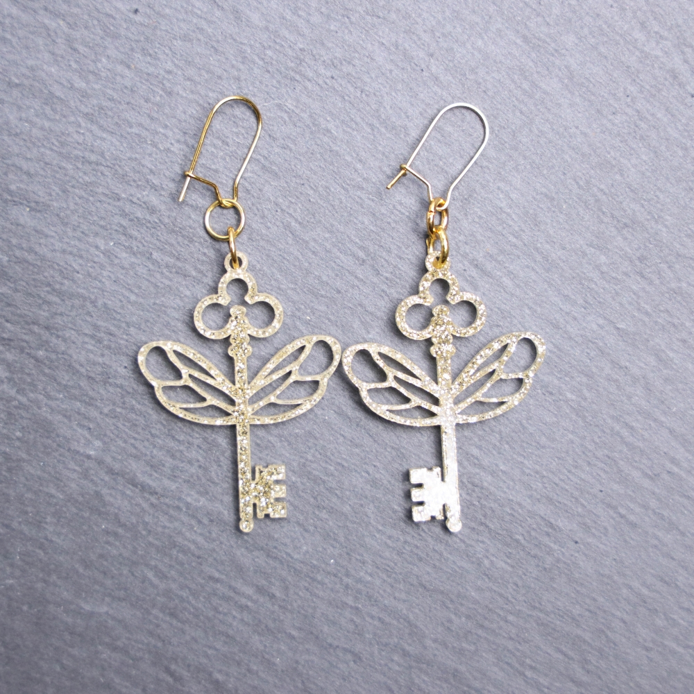Flying Keys Earrings. These earrings are made with gold glitter acrylic. Comes with gold hooks that is nickel free.