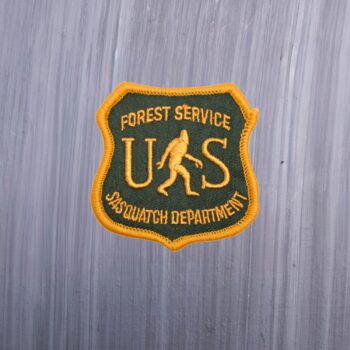 Forest Service Sasquatch Department Patch with a bigfoot on it and US in green and yellow. Beautifully embroidered design with an adhesive for easy application to your favorite bag or article of clothing.
