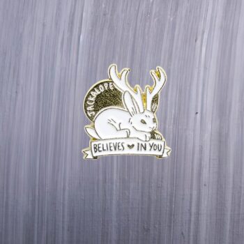 Jackalope Believe In You Enamel Pin in gold and white. These enamel pins are made with metal. These enamel pins are colorful, with a gold colored backing.