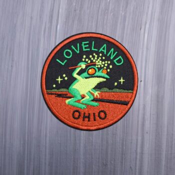 Loveland Ohio Frog Patch with frog in greens with black and dark orange. Beautifully embroidered design with an adhesive for easy application to your favorite bag or article of clothing.