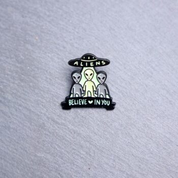 Aliens Believe In You Enamel Pin in black and green. These enamel pins are made with metal. These enamel pins are colorful, with a black backing.