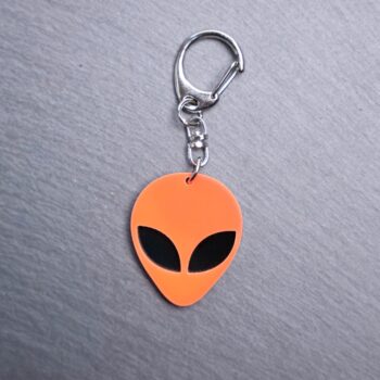 Alien Head Neon Orange Bag Tag with black eyes and black backing. Acrylic designed charm with a swivel lobster snap hook in high quality metal alloy.