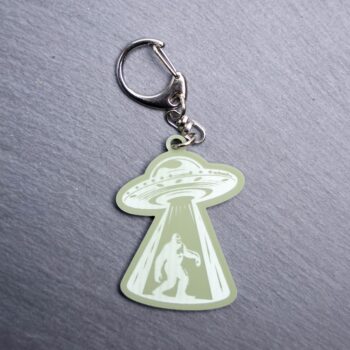 Bigfoot Alien Abduction Green Bag Tag with spaceship. Acrylic designed charm with a swivel lobster snap hook in high quality metal alloy.