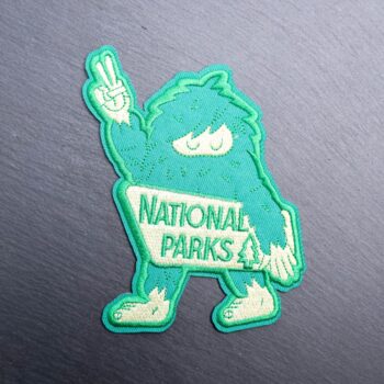 Bigfoot National Parks Patch with green and white bigfoot holding up the peace sign. Beautifully embroidered design with an adhesive for easy application to your favorite bag or article of clothing.