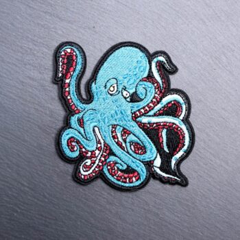 Kraken Patch in a turquoise blue and maroon. Beautifully embroidered design with an adhesive for easy application to your favorite bag or article of clothing.