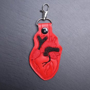 Anatomical Heart Snap Bag Tag. This bag tag is made with faux vinyl and embroidered. Comes with lobster clasp topper that easily hooks to a bag, zippers, keychains