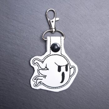 Angry Ghost Snap Bag Tag. This bag tag is made with faux vinyl and embroidered. Comes with lobster clasp topper that easily hooks to a bag, zippers,