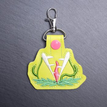 Audrey Snap Bag Tag. This bag tag is made with faux vinyl and embroidered. Comes with lobster clasp topper that easily hooks to a bag, zippers