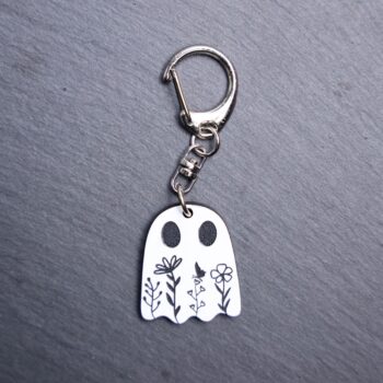 Floral Ghost Bag Tag. This bag tag is made with engraved white and black acrylic. Comes with lobster clasp topper that easily hooks to a bag, zippers, keychains, and lanyards for fun display and swivels. White backside.