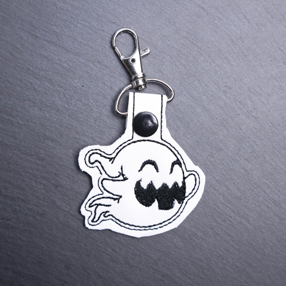 Happy Ghost Snap Bag Tag. This bag tag is made with faux vinyl and embroidered. Comes with lobster clasp topper that easily hooks to a bag, zippers
