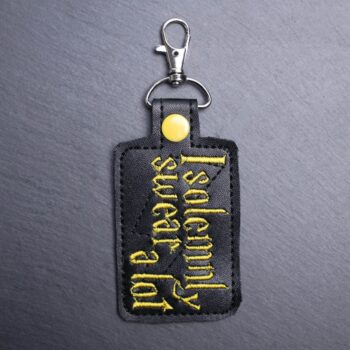 I Solemnly Swear A Lot Snap Bag Tag. This bag tag is made with faux vinyl and embroidered. Comes with lobster clasp topper that easily hooks to a bag, zippers,