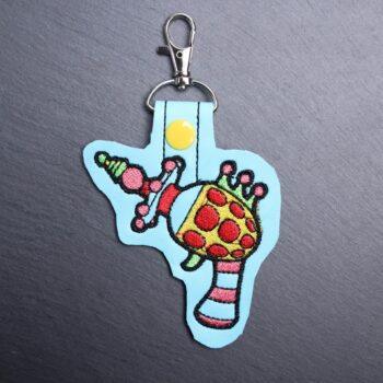 Killer Klowns Gun Snap Bag Tag. This bag tag is made with faux vinyl and embroidered. Comes with lobster clasp topper that easily hooks to a bag, zippers