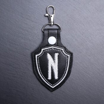 Nevermore Snap Bag Tag. This bag tag is made with faux vinyl and embroidered. Comes with lobster clasp topper that easily hooks to a bag, zippers