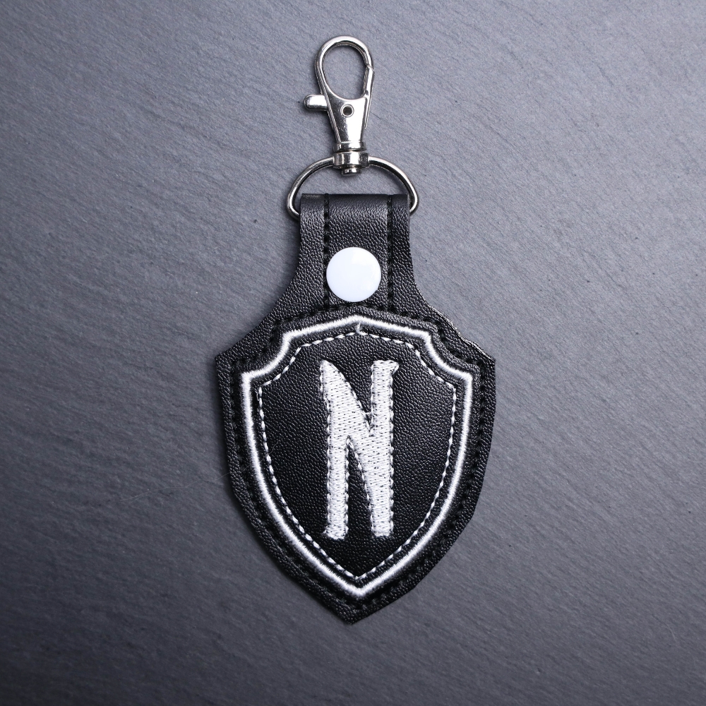 Nevermore Snap Bag Tag. This bag tag is made with faux vinyl and embroidered. Comes with lobster clasp topper that easily hooks to a bag, zippers