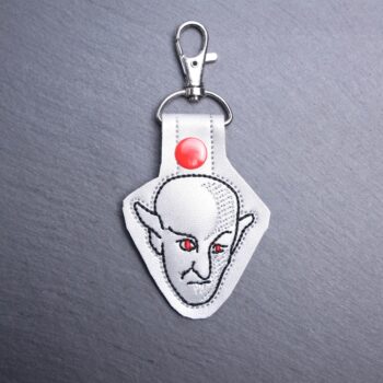 Nosferatu Snap Bag Tag. This bag tag is made with faux vinyl and embroidered. Comes with lobster clasp topper that easily hooks to a bag, zippers