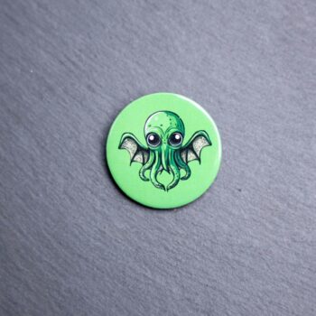 Cthulhu Button. These buttons are made with photo paper, metal round, and metal backing. These buttons are vibrant and fun to use on bags or vests.