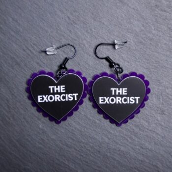 Exorcist Pillow Earrings that are white, black and pink. These earrings are made with engraved acrylic. Comes with black hooks that is nickel free.