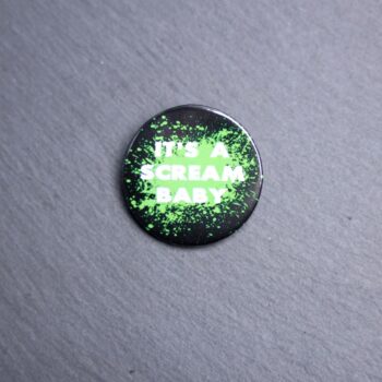 It's A Scream Baby Button. These buttons are made with photo paper, metal round, and metal backing. These buttons are vibrant and fun to use on bags or vests.