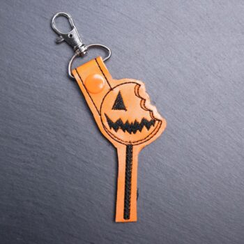 Pumpkin Lollipop Snap Bag Tag. This bag tag is made with faux vinyl and embroidered. Comes with lobster clasp topper that easily hooks to a bag, zippers
