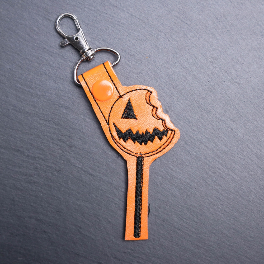 Pumpkin Lollipop Snap Bag Tag. This bag tag is made with faux vinyl and embroidered. Comes with lobster clasp topper that easily hooks to a bag, zippers