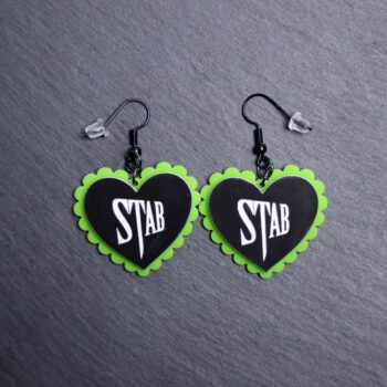 Stab Pillow Earrings that are white, black and green. These earrings are made with engraved acrylic. Comes with black hooks that is nickel free.