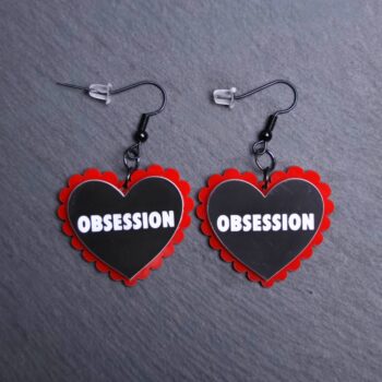 Obsession Pillow Earrings that are white, black and red. These earrings are made with engraved acrylic. Comes with black hooks that is nickel free.