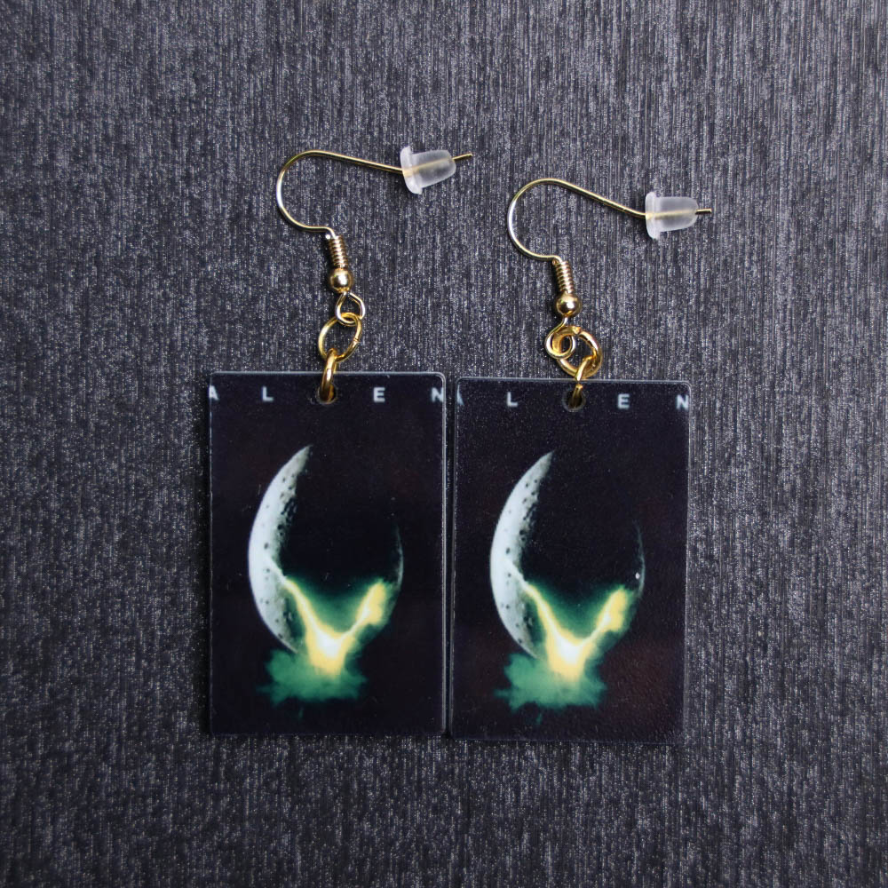 Alien Poster Earrings. These earrings are made with acrylic and hand heat pressed. Comes with 18k plated gold hooks that is nickel free.