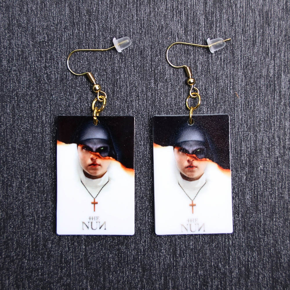 Nun Poster Earrings. These earrings are made with acrylic and hand heat pressed. Comes with 18k plated gold hooks that is nickel free.