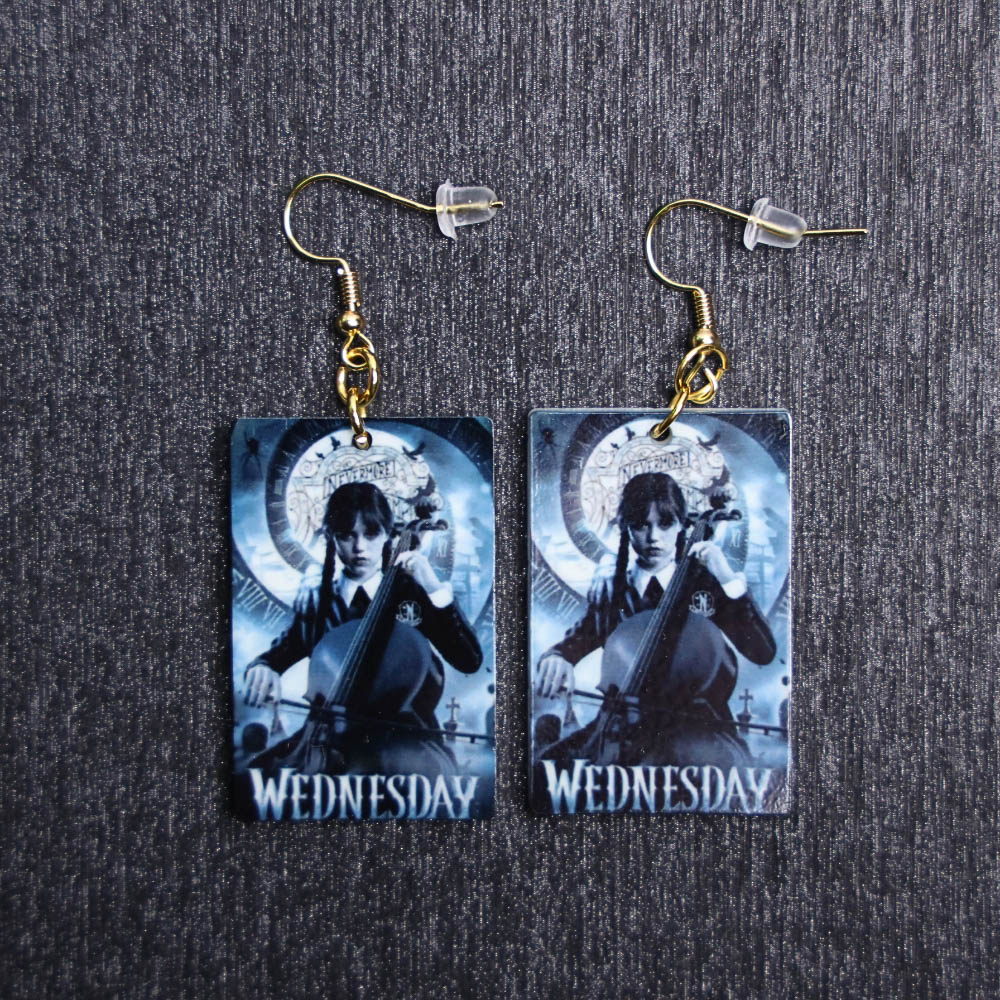 Wednesday Addams Poster Earrings. These earrings are made with acrylic and hand heat pressed. Comes with 18k plated gold hooks that is nickel free.