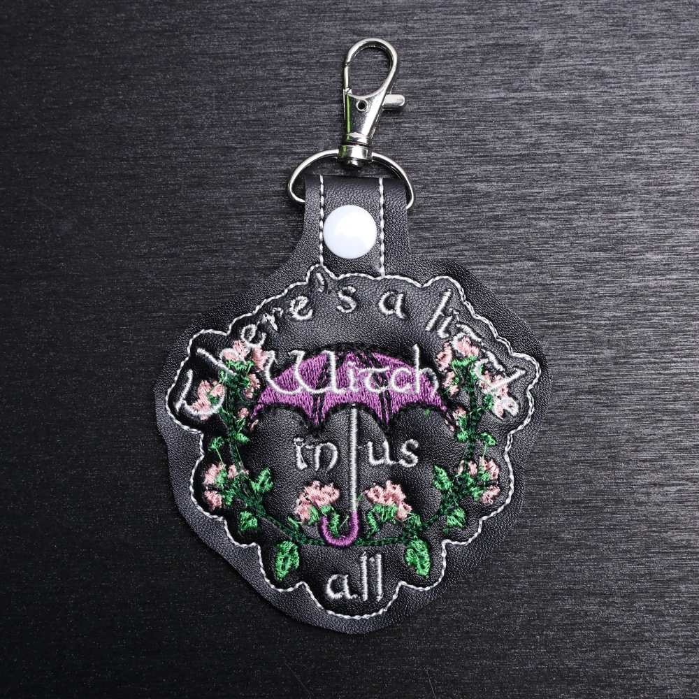 A Little Witch Practical Magic Bag Tag. This bag tag is made with faux vinyl and embroidered. Comes with lobster clasp topper that easily hooks to a bag, zippers,